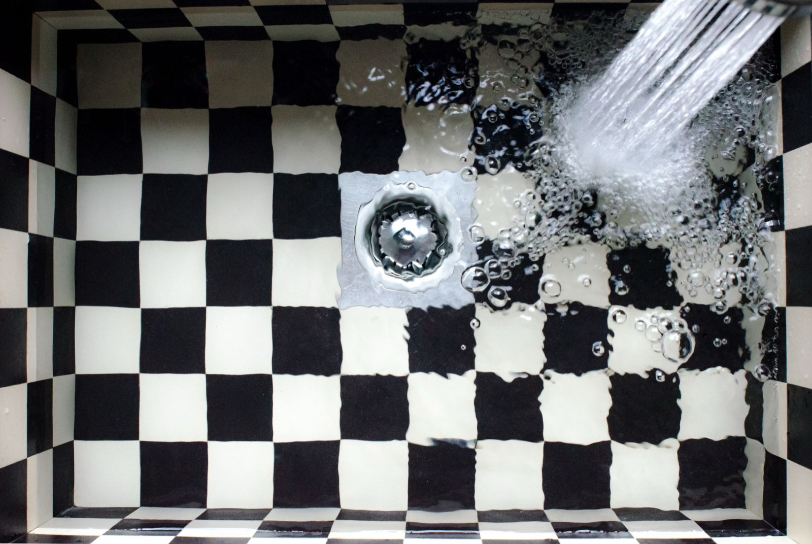 Évier de cuisine dont l'eau s'écoule lentement par la bonde, premier signe d'une évacuation encrassée